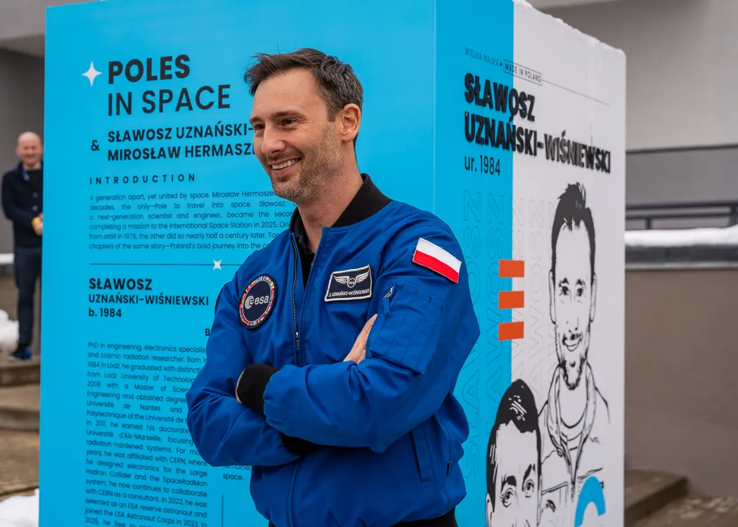 Spotkanie ze Sławoszem Uznańskim-Wiśniewskim na UWM: Sławosz Uznański-Wiśniewski pozuje do zdjęcie przy wystawie Kortosfery