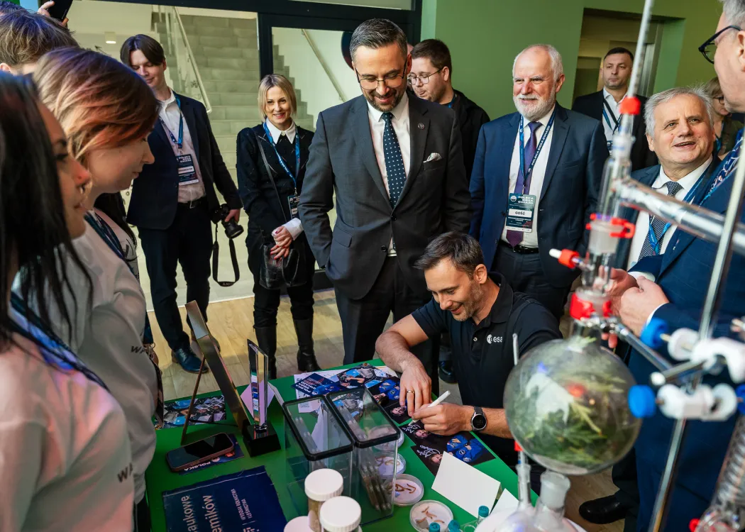 Spotkanie ze Sławoszem Uznańskim-Wiśniewskim na UWM: dr Sławosz Uznański-Wiśniewski daje autograf na stoisku koła naukowego