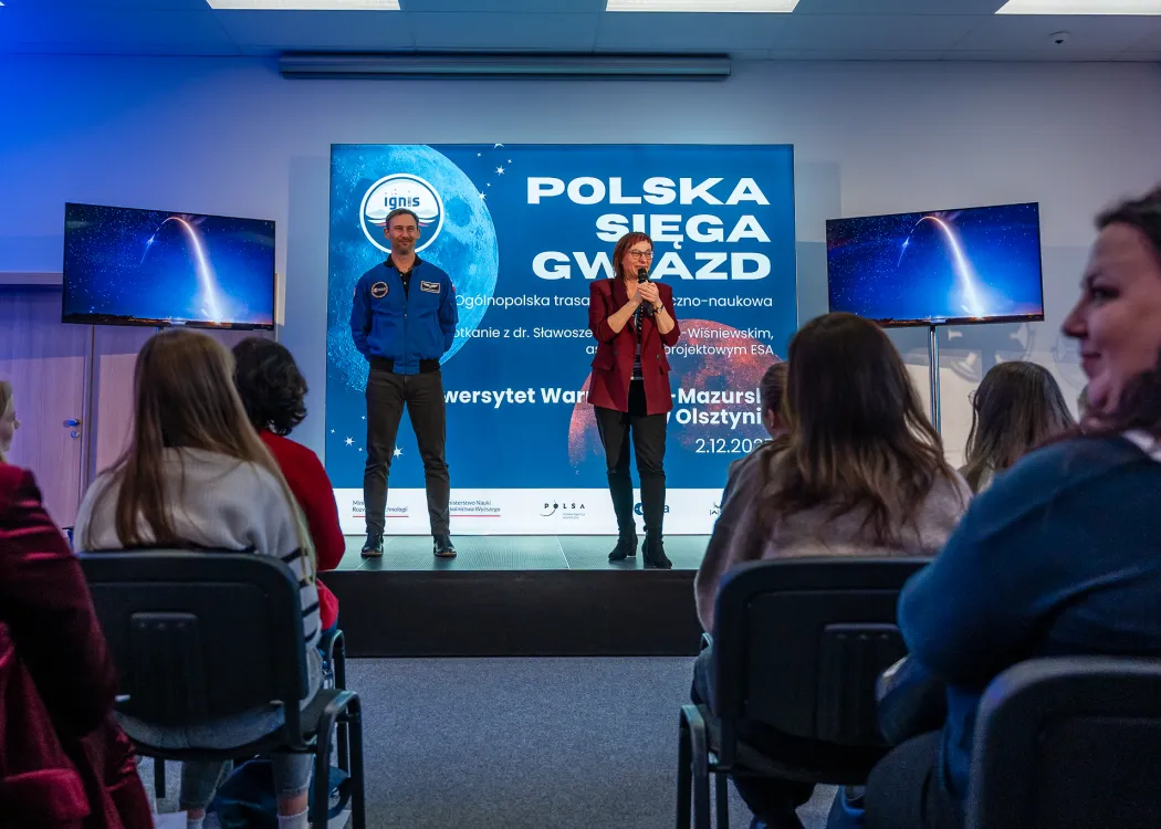 Spotkanie ze Sławoszem Uznańskim-Wiśniewskim na UWM: dr inż. Sławosz Uznański-Wiśniewski stoi na scenie podczas spotkania z dziećmi i młodzieżą