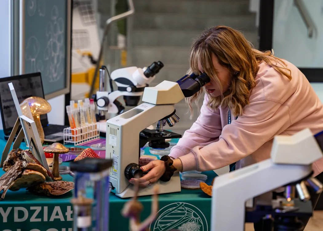 Spotkanie ze Sławoszem Uznańskim-Wiśniewskim na UWM: dziewczyna patrzy w mikroskop 