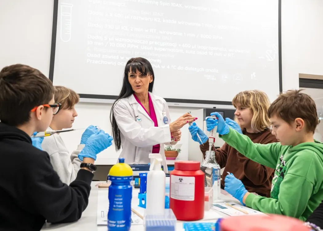 Noc Biologów 2026: prowadząca zajęcia, pojemniki z płynami i uczestnicy