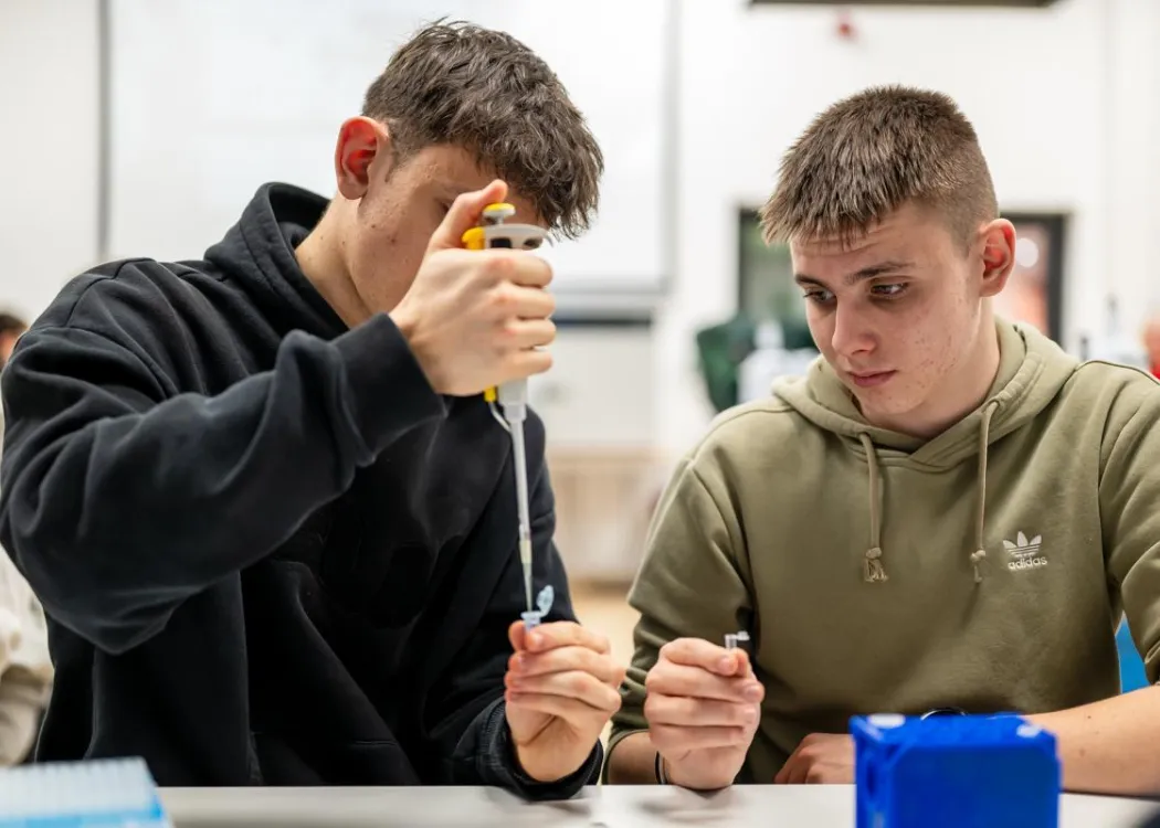 Noc Biologów 2026: uczestnicy zajęć siedzą przy stole w laboratorium