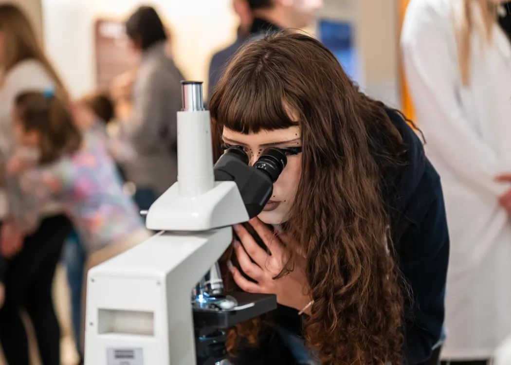 Noc Biologów 2026: kobieta patrzy przez mikroskop
