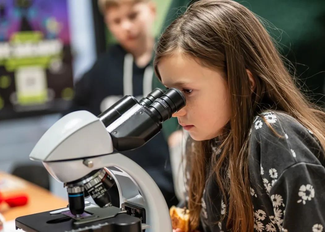 Noc Biologów 2026: dziewczynka patrzy przez mikroskop 