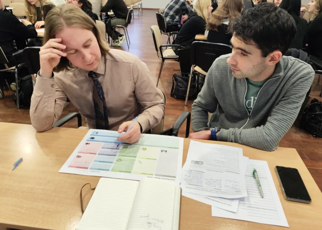 studenci siedzą i omawiają plan biznesowy przedsiębiorstwa społecznego