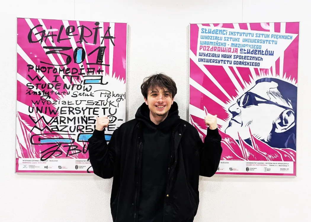 Chłopiec w czarnej bluzie na tle plakatu wystawy 