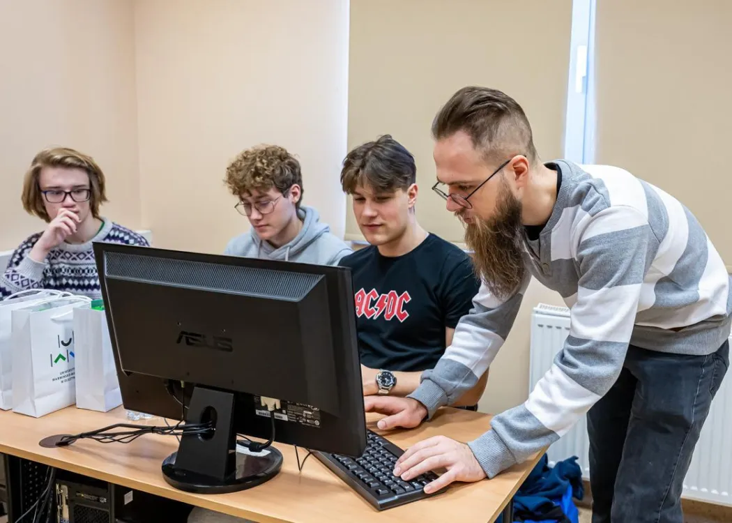 Młodzież siedzi przy komputerze podczas zespołowych zawodów programowania