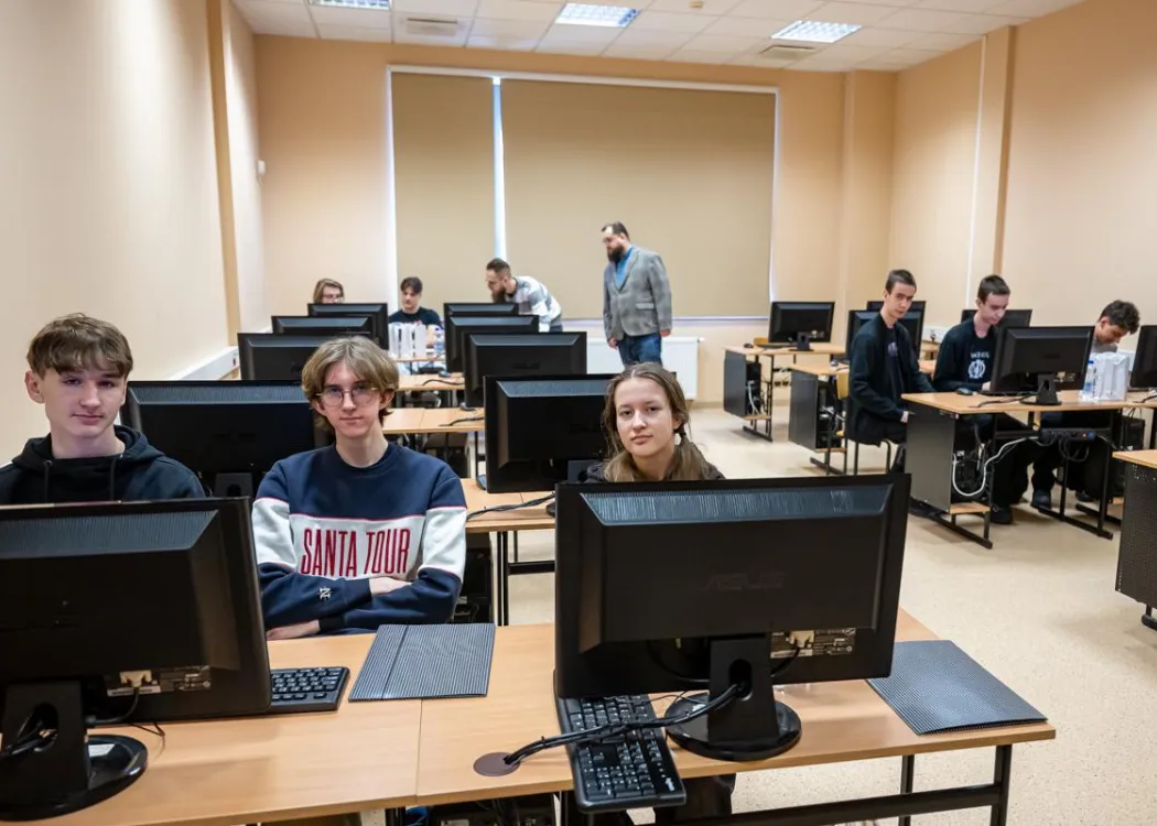 Młodzież siedzi przy komputerze podczas zespołowych zawodów programowania
