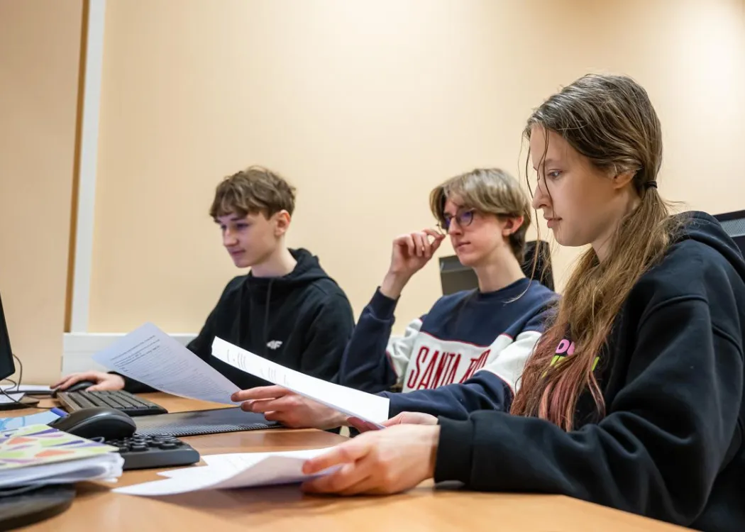 Młodzież siedzi przy komputerze podczas zespołowych zawodów programowania