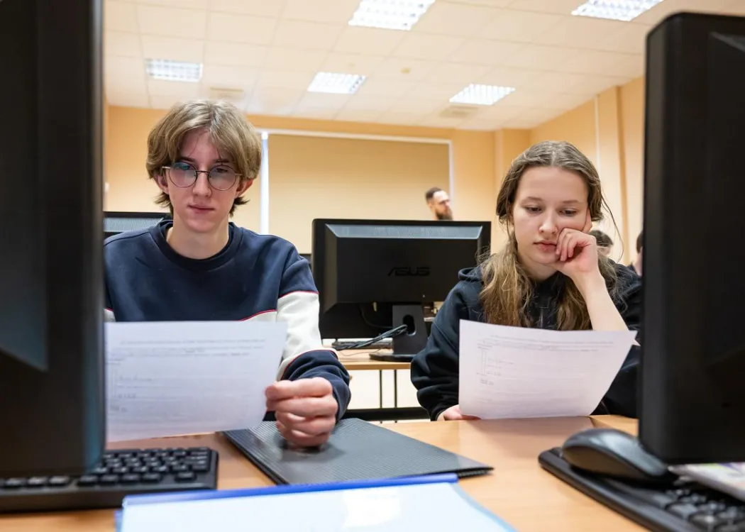 Młodzież siedzi przy komputerze podczas zespołowych zawodów programowania