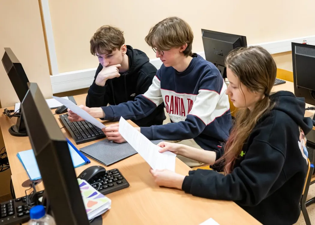 Młodzież siedzi przy komputerze podczas zespołowych zawodów programowania