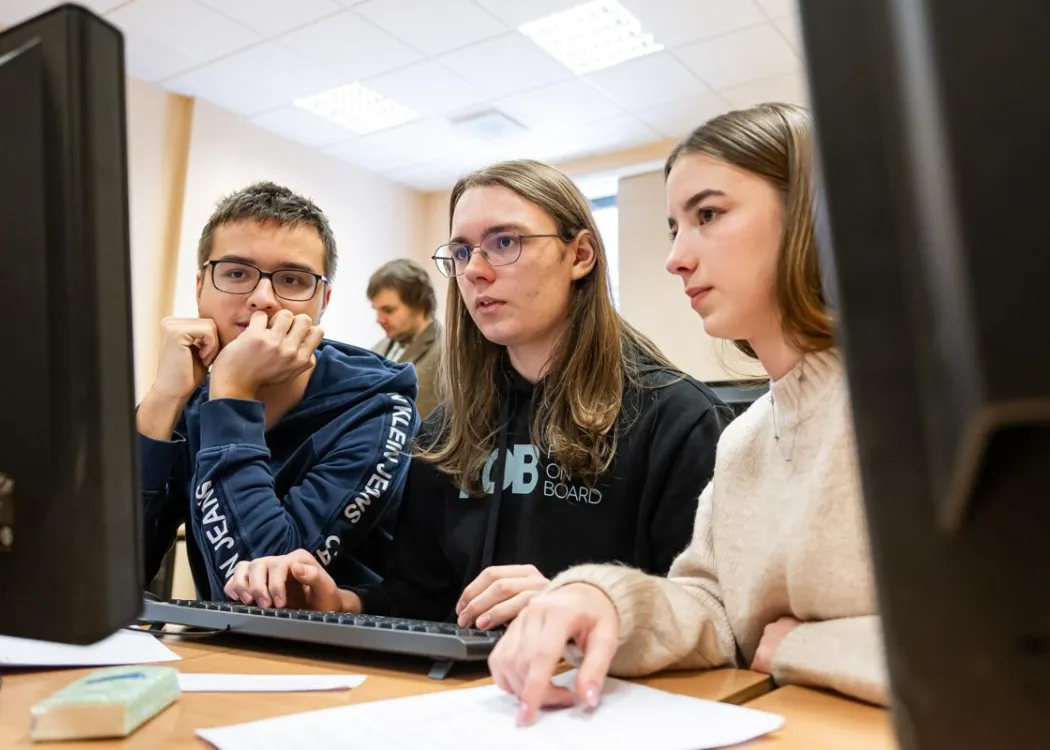 Młodzież siedzi przy komputerze podczas zespołowych zawodów programowania