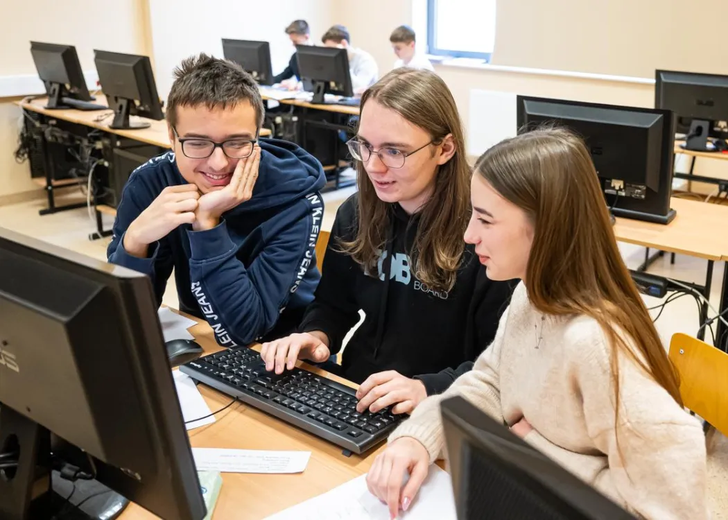 Młodzież siedzi przy komputerze podczas zespołowych zawodów programowania