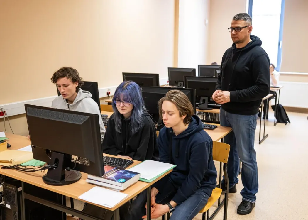 Młodzież siedzi przy komputerze podczas zespołowych zawodów programowania