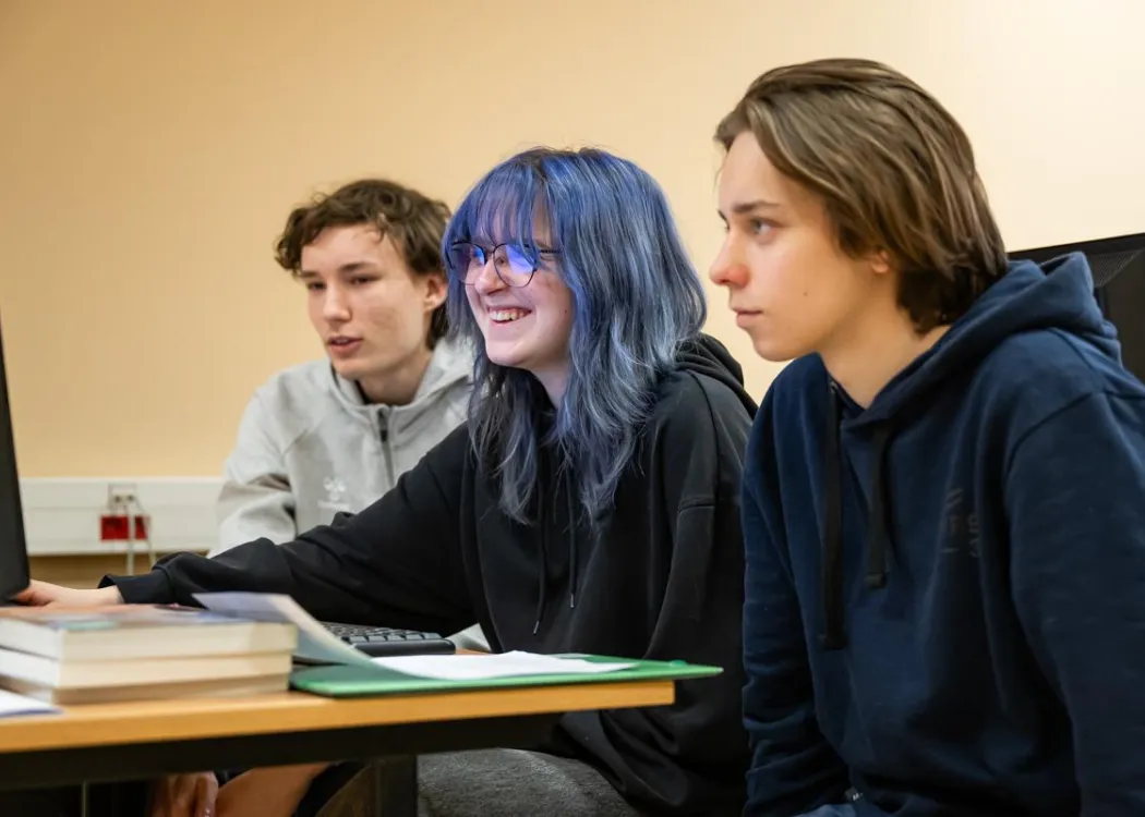 Młodzież siedzi przy komputerze podczas zespołowych zawodów programowania