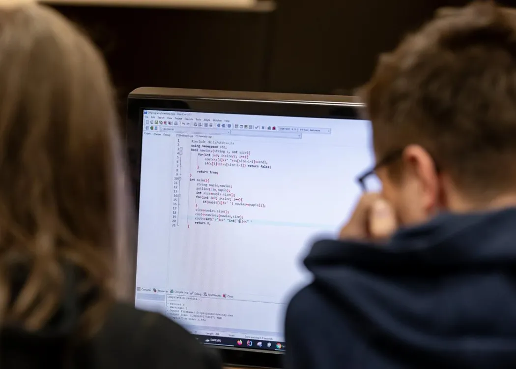 Młodzież siedzi przy komputerze podczas zespołowych zawodów programowania