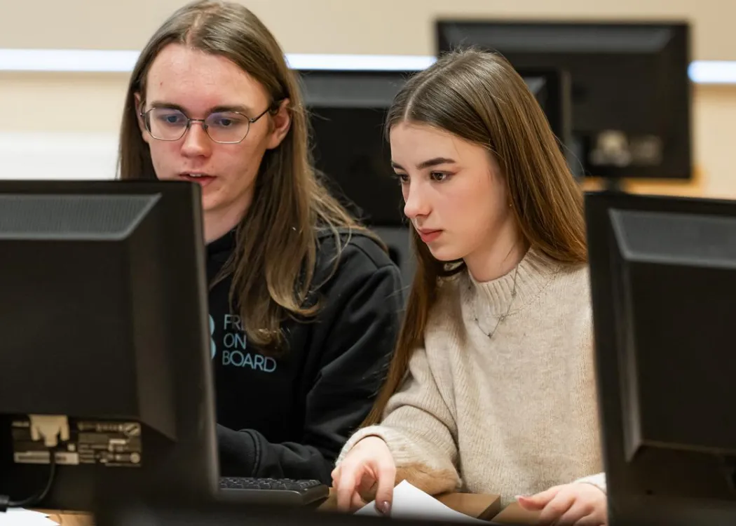 Młodzież siedzi przy komputerze podczas zespołowych zawodów programowania