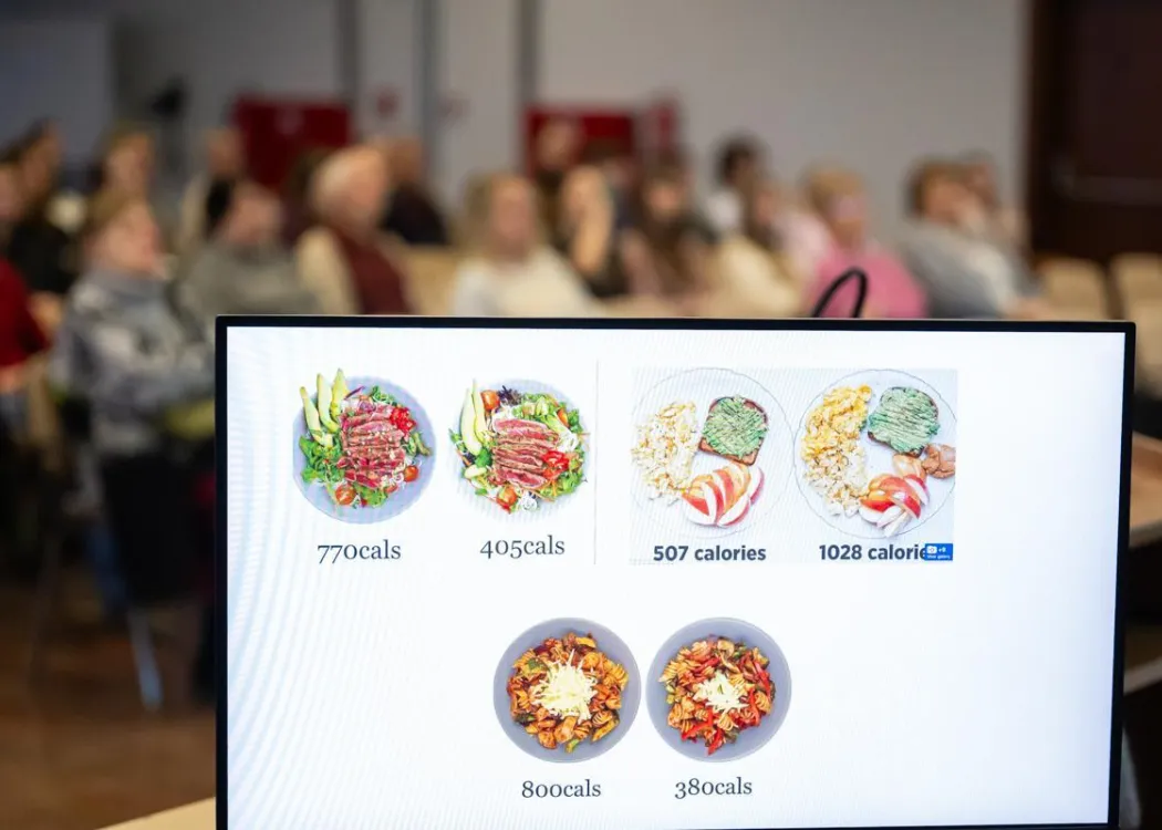 Na pierwszym planie mointor z fragmentem prezentacji, na drugim - uczestnicy spotkaia