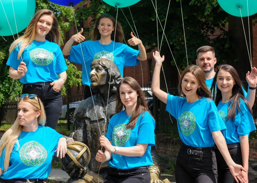 Studenci z balonami pozują przy pomniku Mikołaja Kopernika