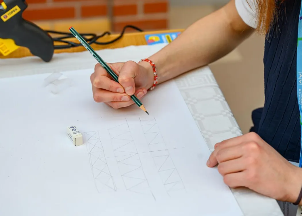 BIP na Wydziale Geoinżynierii UWM: zdjęcie pokazuje rękę trzymającą ołówek i kartkę papieru jednego z uczestników warsztatów