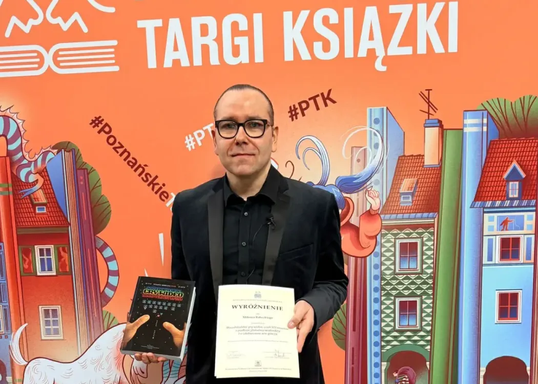 Dr hab. Miłosz Babecki pozuje z książką i dyplomem 