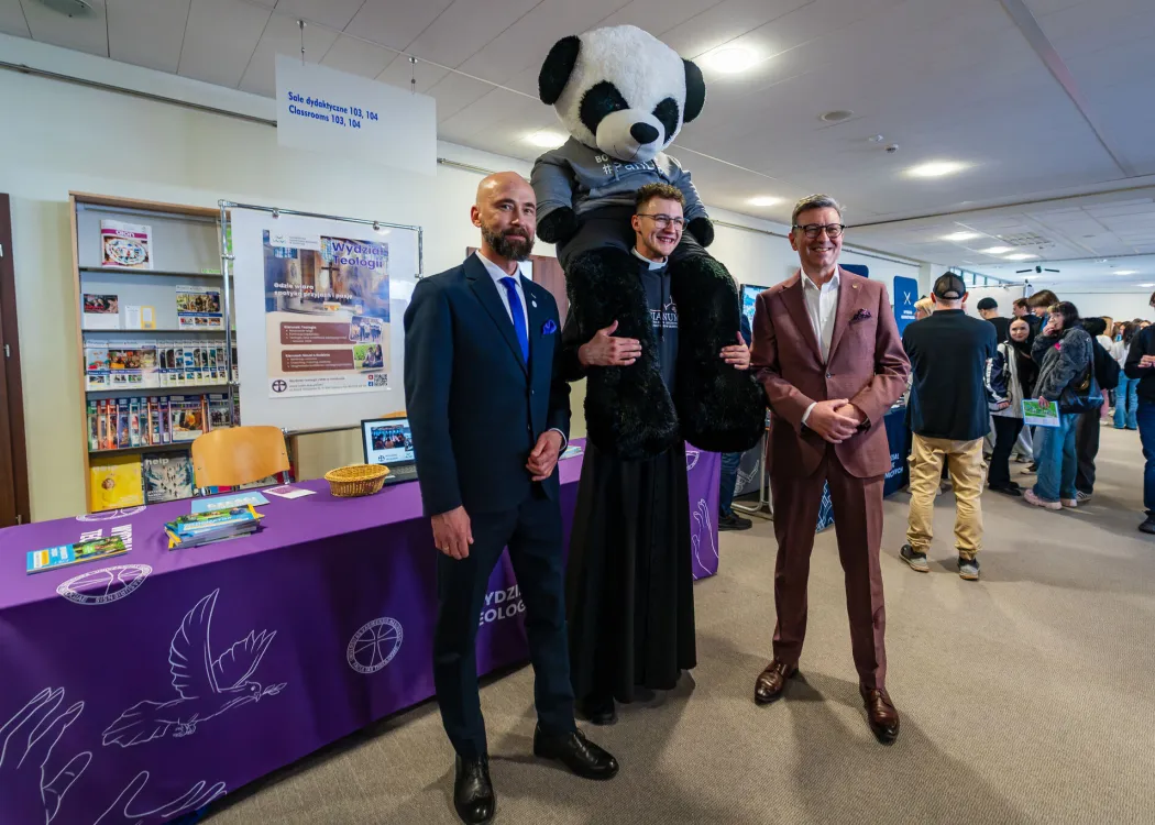 Dzień Otwarty UWM 2026: Sławomir Przybyliński, przedstawiciel Wydziału Teologii i Jerzy Przyborowski pozują do zdjęcia z dużą pluszową pandą