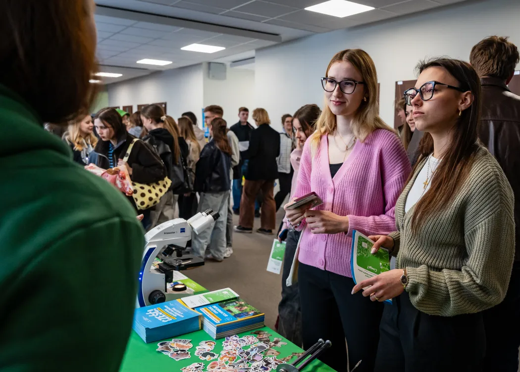 Dzień Otwarty UWM 2026: uczestniczki wydarzenia odwiedzają jedno ze stoisk