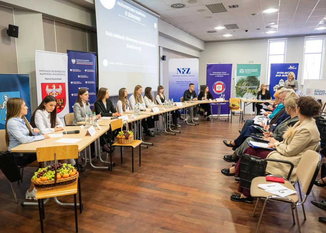 Uczestnicy finału Ogólnopolskiej Olimpiady o Zdrowiu siedzą przy stołach, przed nimi - widownia