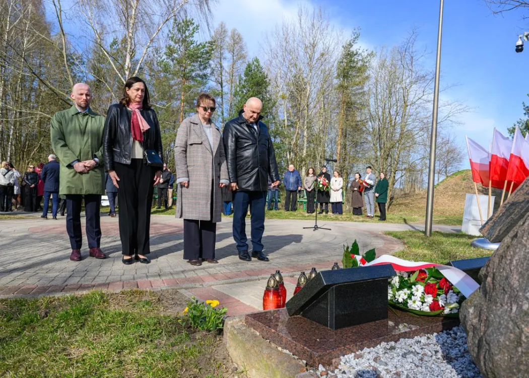Uczestnicy uroczystości upamiętniającej ofiary zbrodni katyńskiej składają kwiaty pod tablicą pamiątkową. 