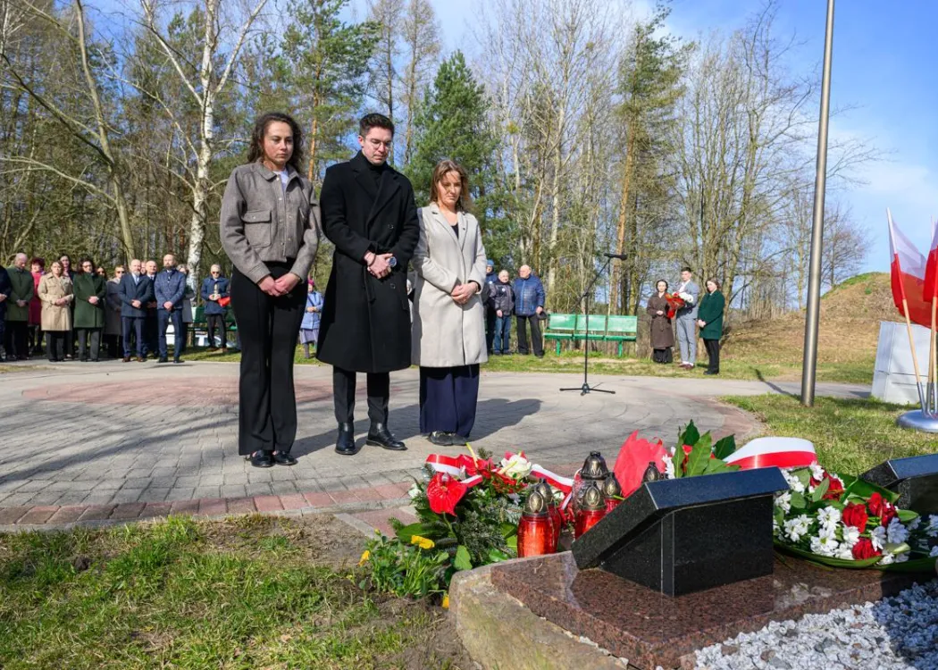 Uczestnicy uroczystości upamiętniającej ofiary zbrodni katyńskiej składają kwiaty pod tablicą pamiątkową.