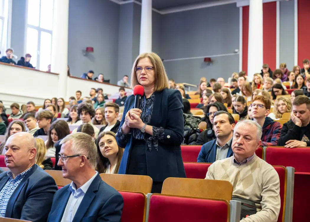Naukowczyni zadaje pytanie, uczestnicy siedzą 
