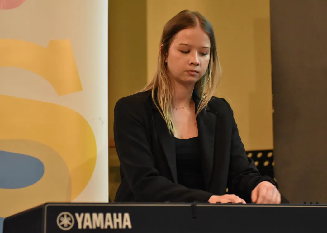 Studentka gra na klawiszach na scenie podczas koncertu 