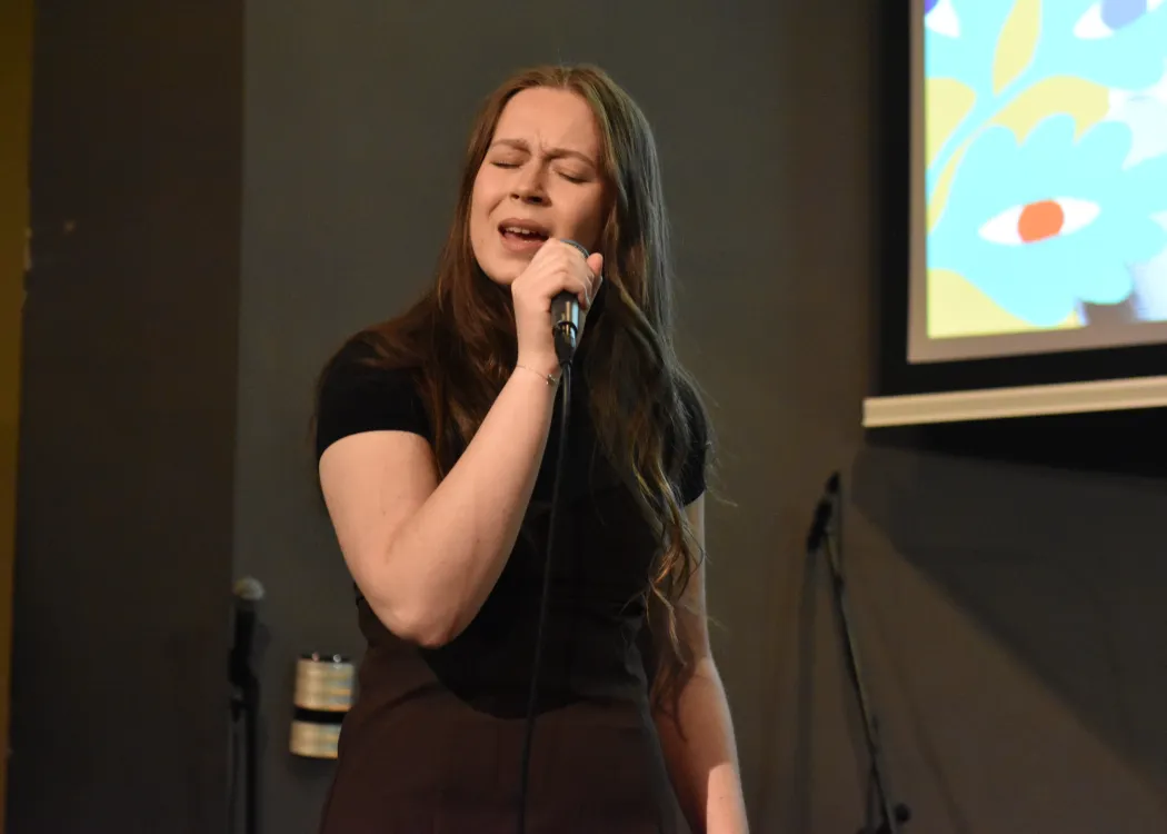 Studentka śpiewa na scenie podczas koncertu 