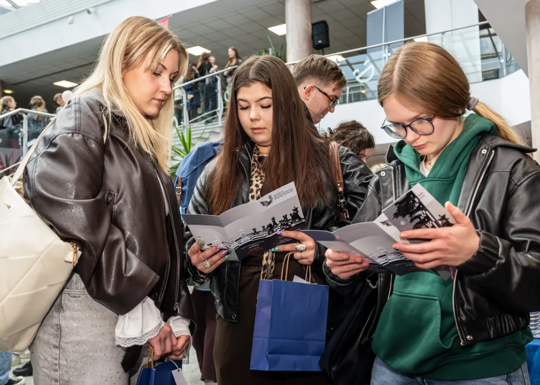 Targi Pracy UWM 2026: Uczestniczki targów czytają folder informacyjny