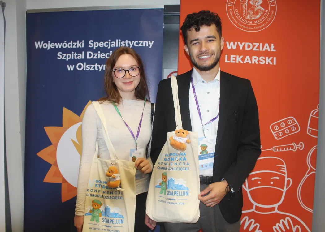 Dwoje studentów pozuje z gadżetami konferencji Scalpellum