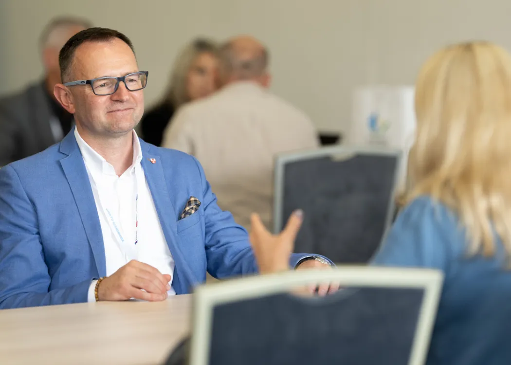 przedsiębiorcy podczas rozmów B2B, siedzą przy stole i przedstawiają ofertę swoich firm