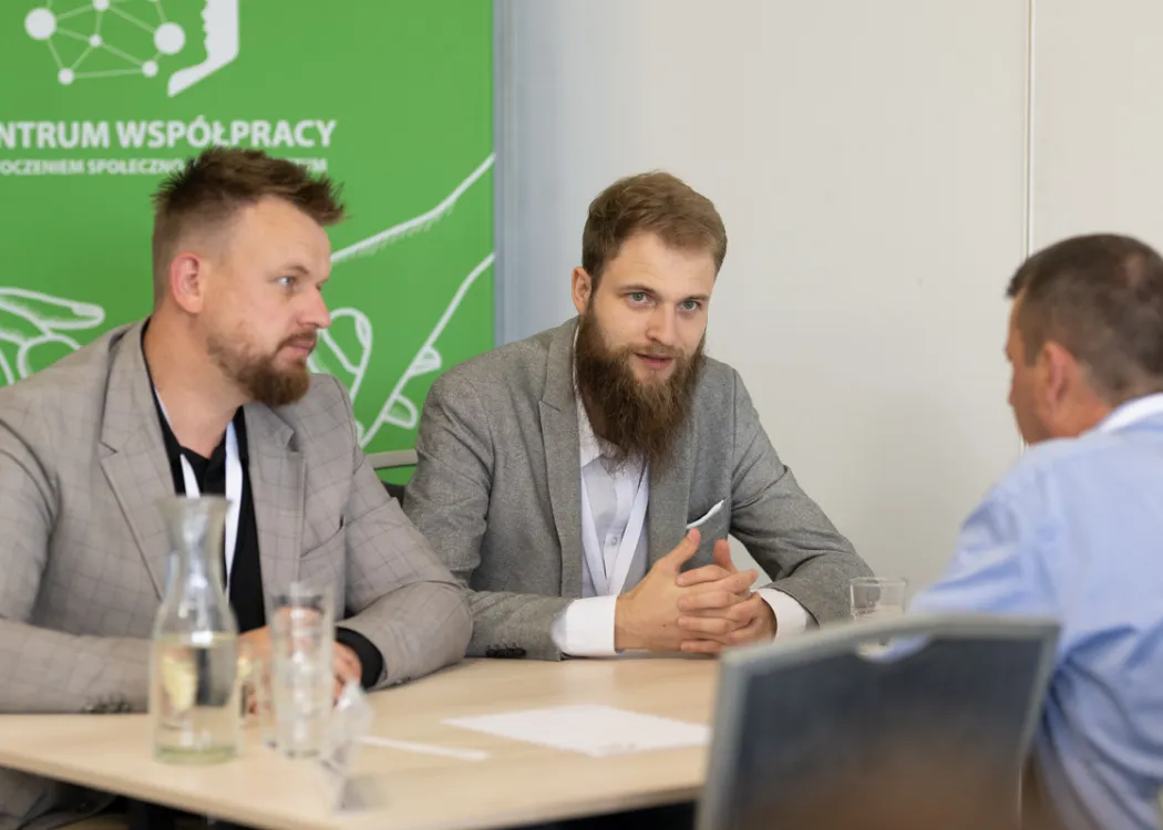 przedsiębiorcy podczas rozmów B2B, siedzą przy stole i przedstawiają ofertę swoich firm