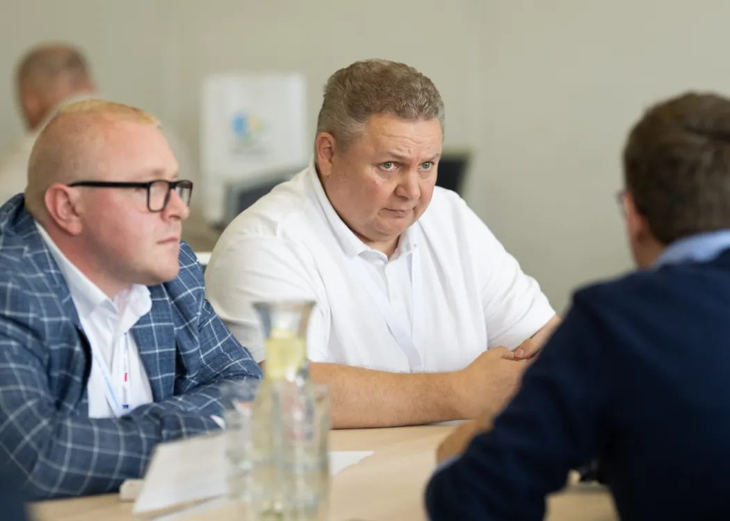 przedsiębiorcy podczas rozmów B2B, siedzą przy stole i przedstawiają ofertę swoich firm