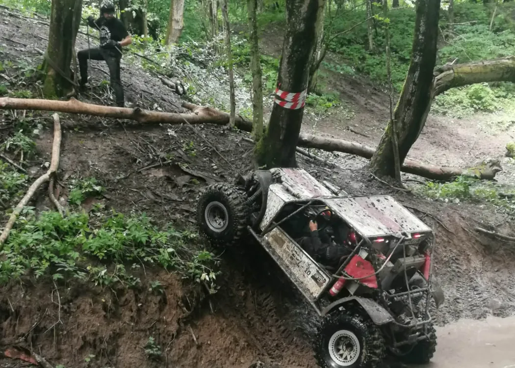 Mężczyzna ciągnie na linie pod górę samochód terenowy