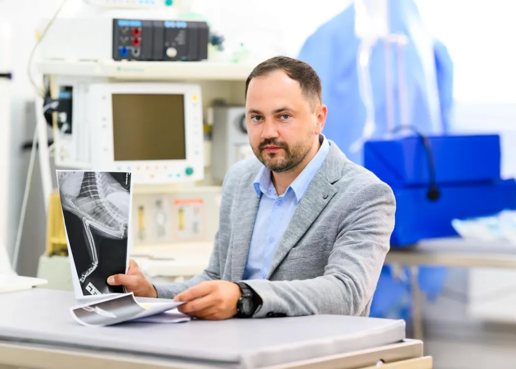 Prof. dr hab. wet. Yauheni Zhalniarovich siedzi przy biurku i trzyma w rękach zdjęcie rentgenowskie