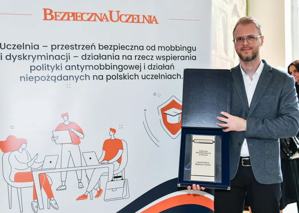 Rzecznik ds. równości szans pozuje z nagrodą Bezpieczna Uczelnia dla UWM