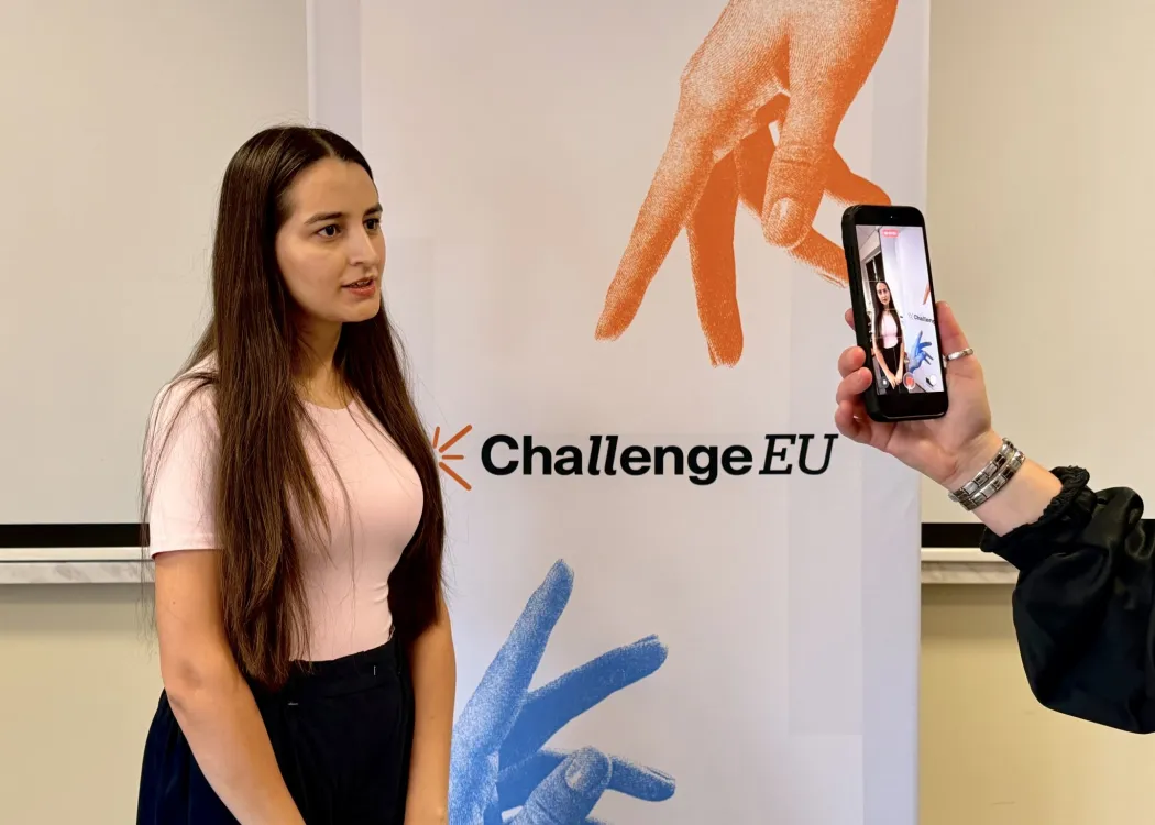 Studentka udziela wywiadu, stojąc przy banerze ChallengeEU