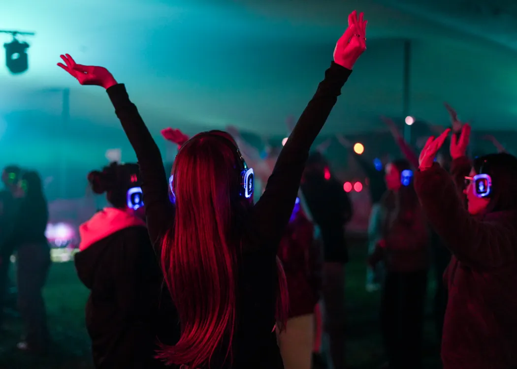Impreza silent party. Dziewczyna podczas zabawy unosi radośnie obie ręce