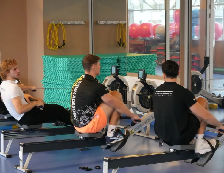 mężczyźni ćwiczący na ergometrach wioślarskich 