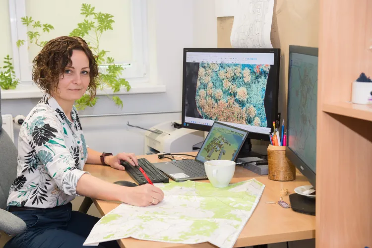 Renata Pelc-Mieczkowska siedzi przy biurku i czyta mapy 