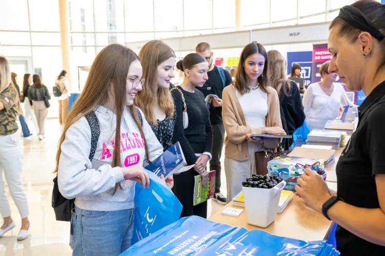 Kilka dziewczyn stoi przy stoisku UWM