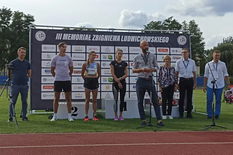 Sławomir Przybyliński stoi ze sportowcami i Piotrem Grzymowiczem 