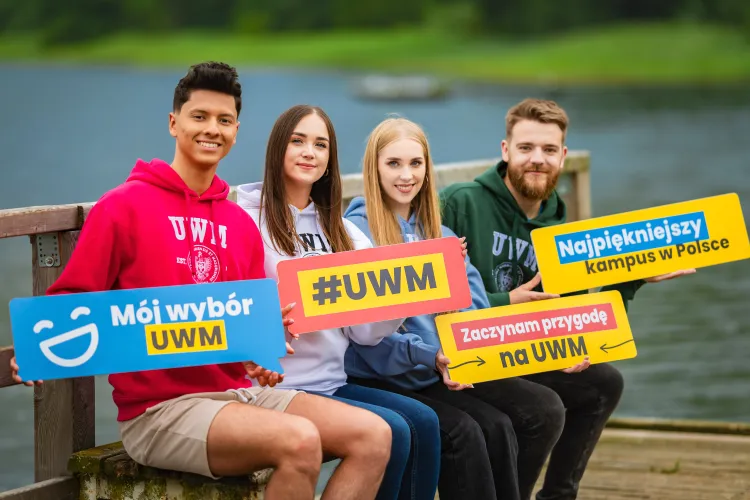 Studenci UWM pozują z tabliczkami z napisami zachęcającymi do studiowania w Kortowie