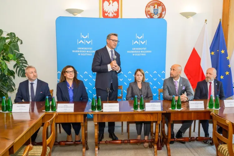 Rektor stoi i przemawia wśród prorektorów 