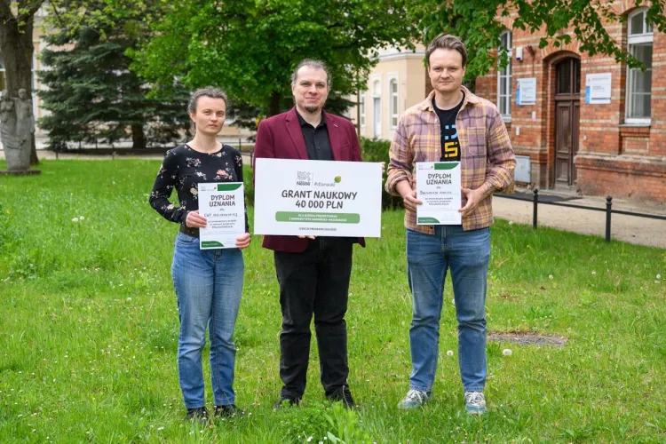 trzyosobowy zespół badawczy stoi z tablicami informującymi o grancie Nestle 